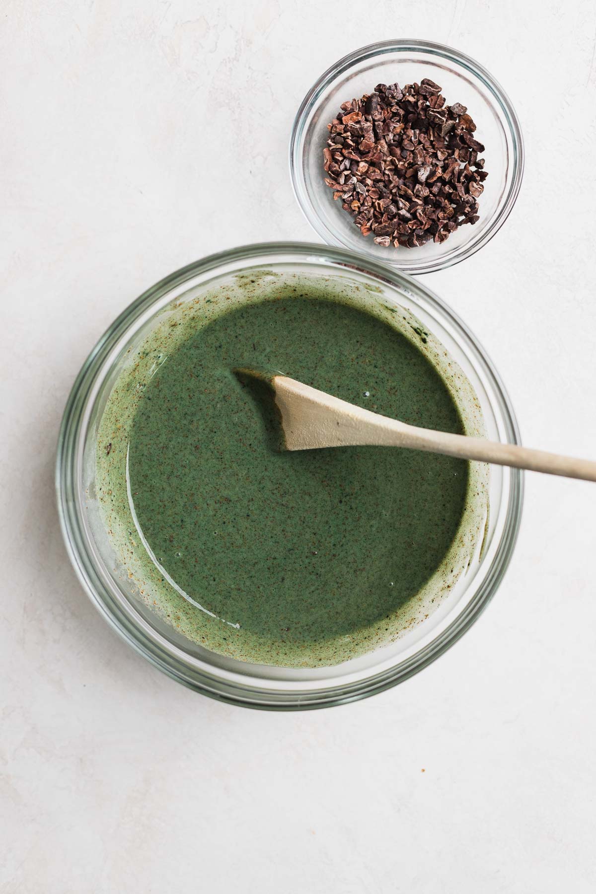 Spirulina green mint mixture in a glass mixing bowl with a wooden spoon.
