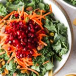 the best kale salad in a bowl with pomegranate and lemons