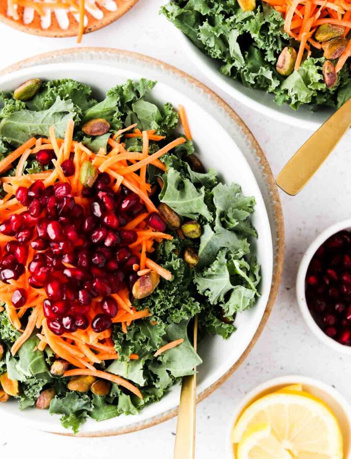 the best vegan kale salad in 2 bowls with pistachios, pomegranate and carrots