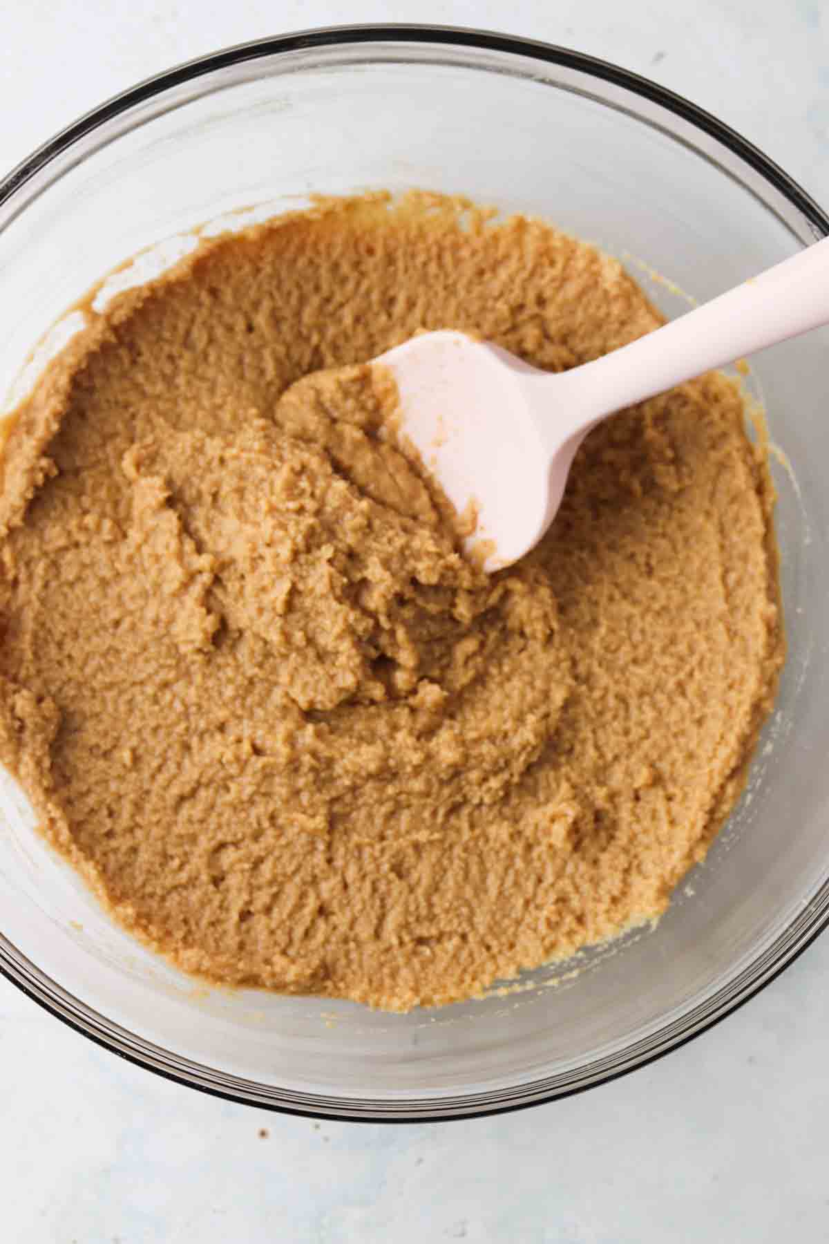 Wet and dry cupcake ingredients mixed in a glass mixing bowl.