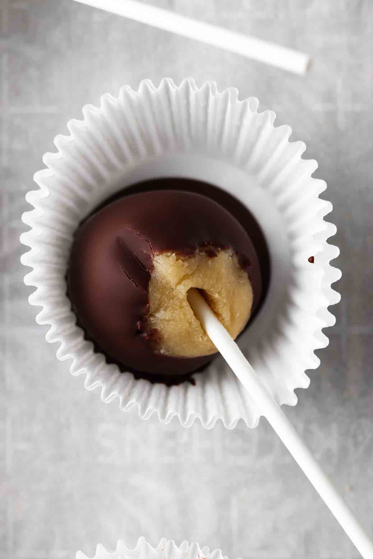 Cookie cake pops dipped in chocolate inside of a muffin liner.