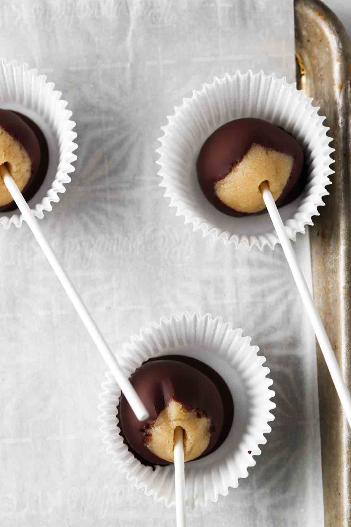 Gluten free cake pops in muffin liners lined on a baking sheet.