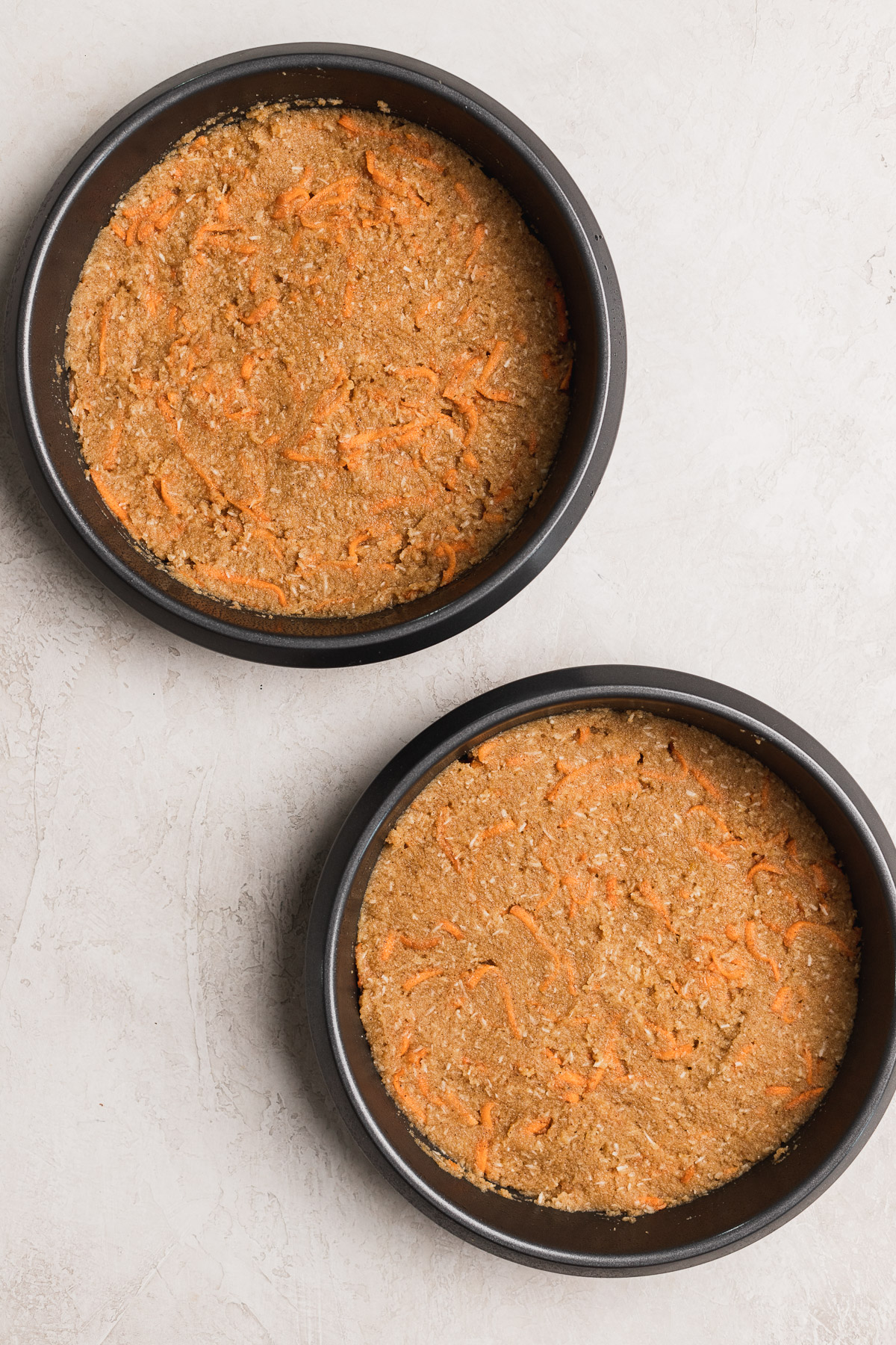 Raw carrot cake batter divided up into two 8 inch cake pans. 