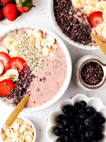 strawberry banana smoothie bowl in a bowl with berries on top