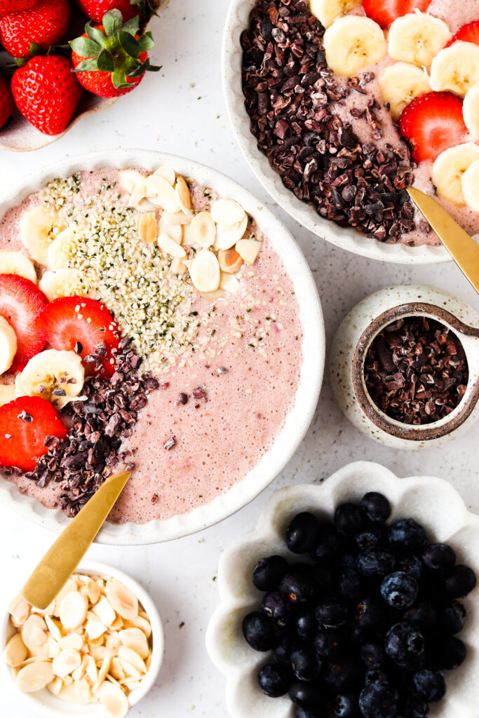 strawberry banana smoothie bowl in a bowl with berries on top