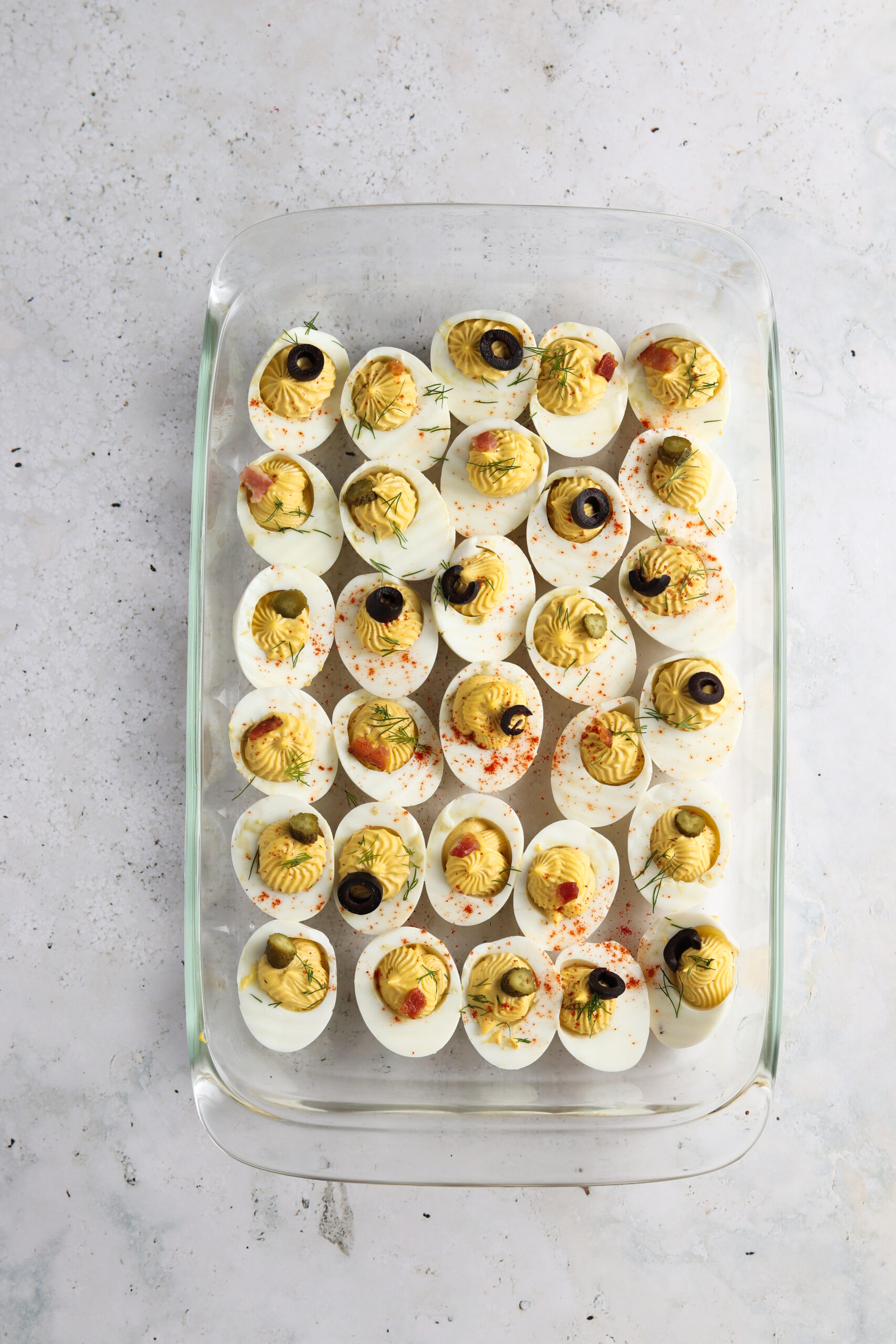 Decorated deviled eggs on a cutting board with fun garnishes on top.