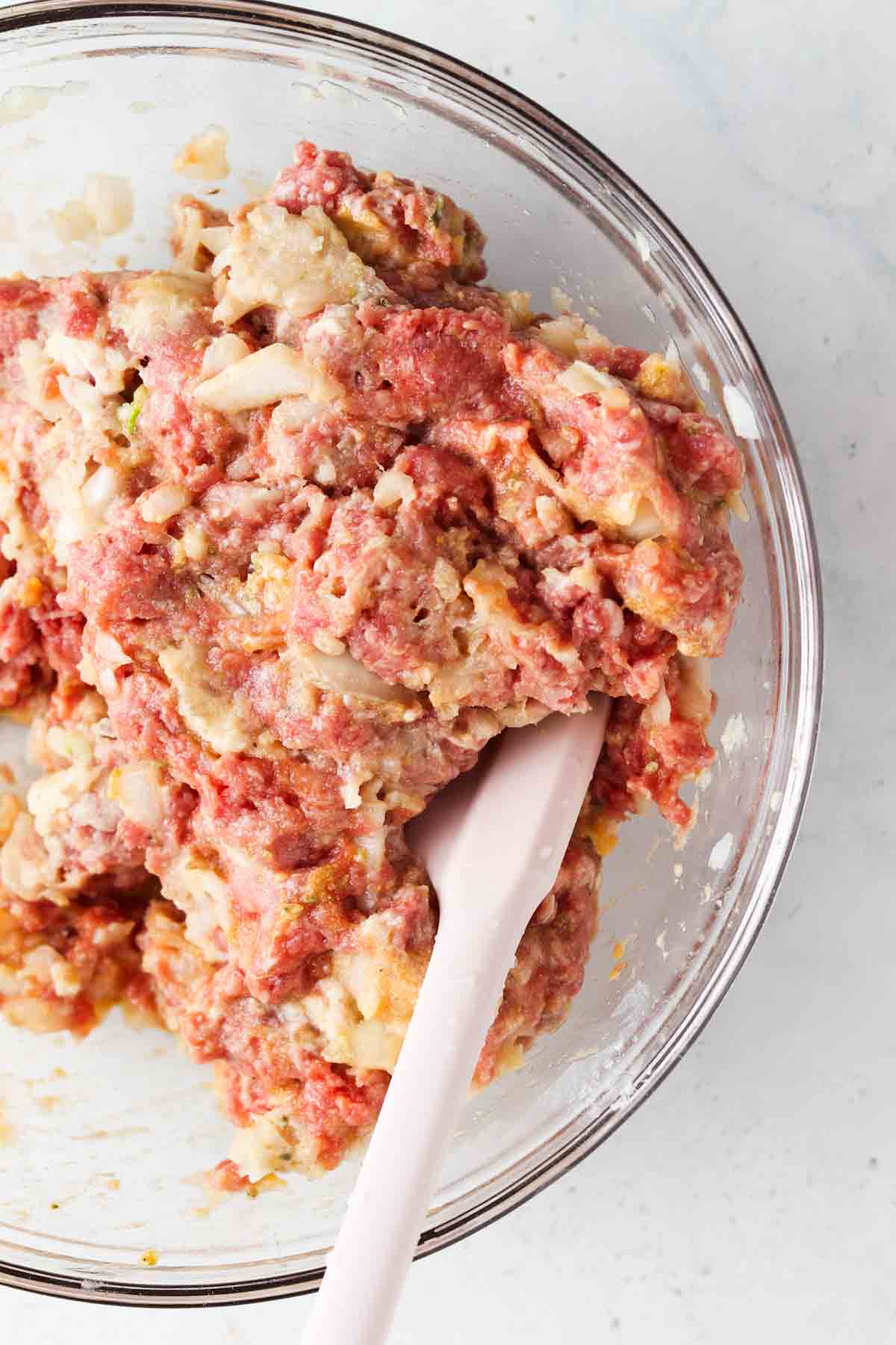 Meatball ingredients mixed in a clear bowl.