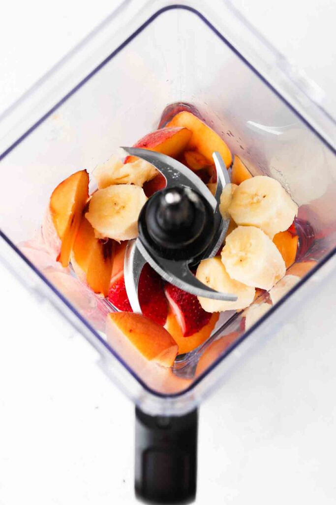 bananans, coconut water, strawberries, and peaches in a blender