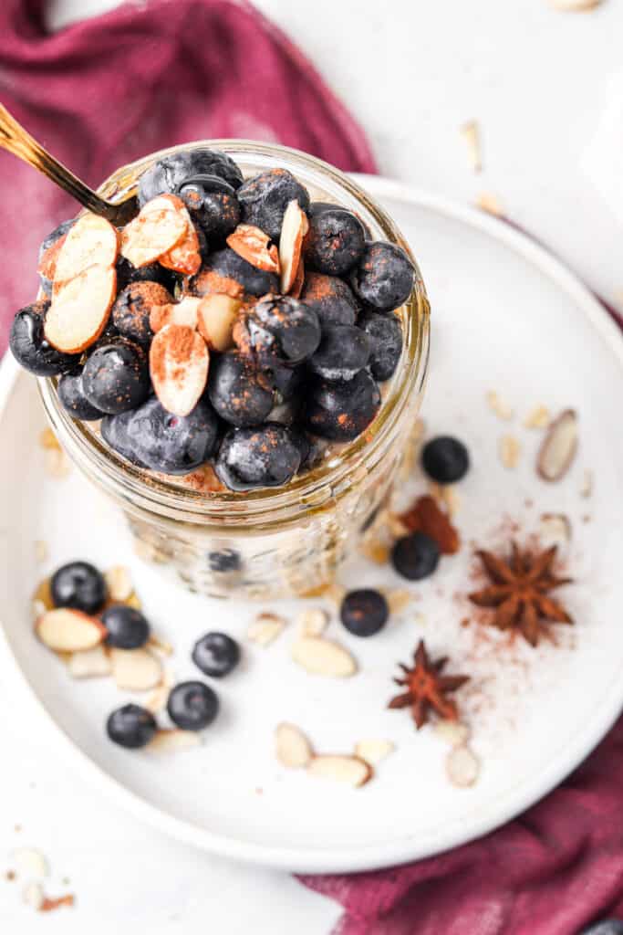 blueberry banana overnight oats overhead shot with white plate and purple cloth