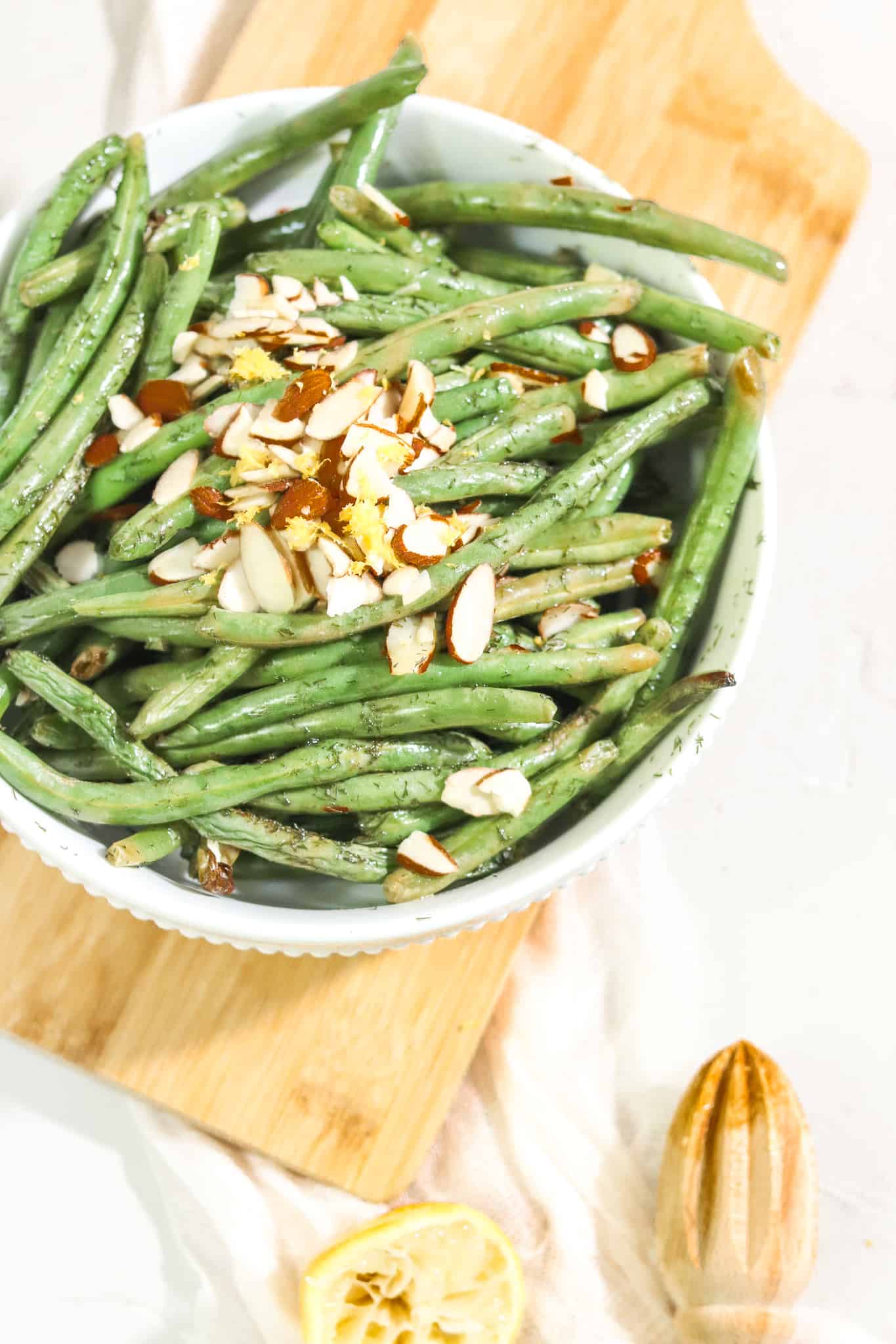 Lemon dill green beans in a serving bowl on a wooden platter.