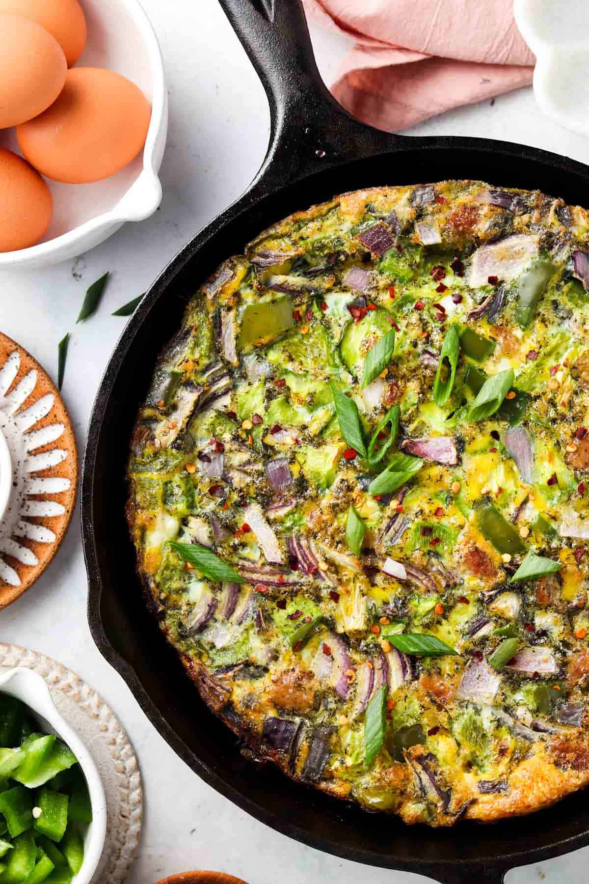 Egg frittata in a cast iron pan with fresh pepper on top.