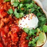 close up photo of chili in a bowl with limes