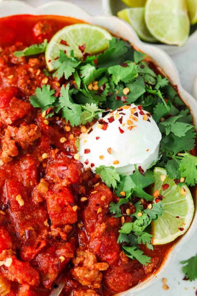 close up photo of chili in a bowl with limes