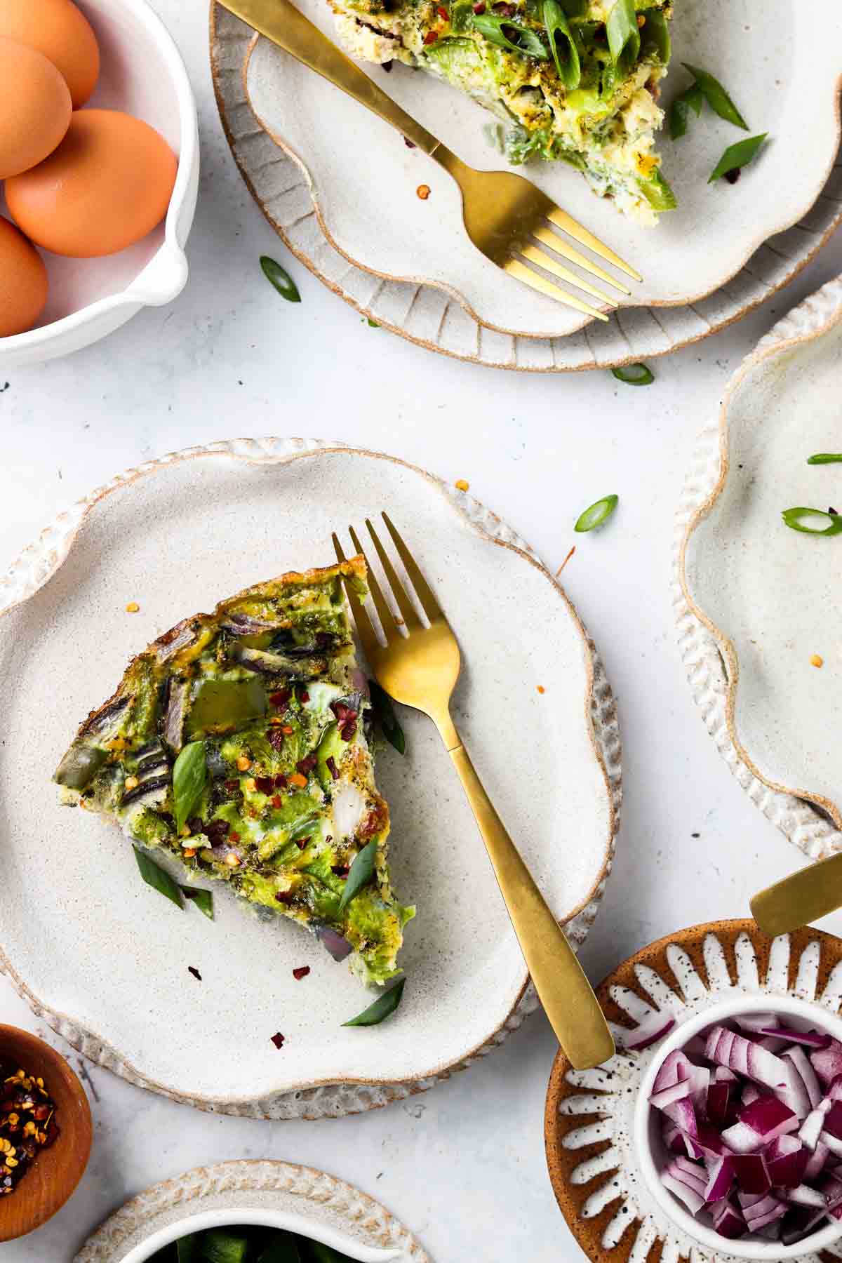 Keto frittata on a plate with a fork and green onions on top. 