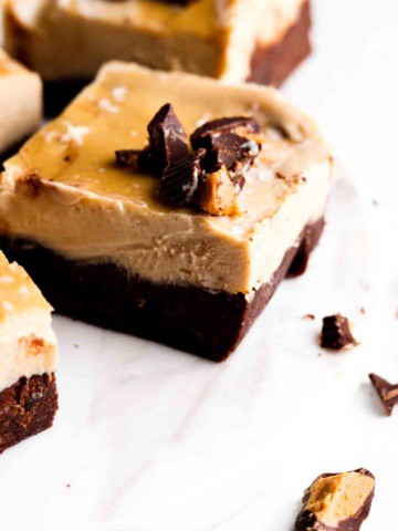 Cashew cream peanut butter vegan cheesecake bars with a chocolate crust on a white plate.