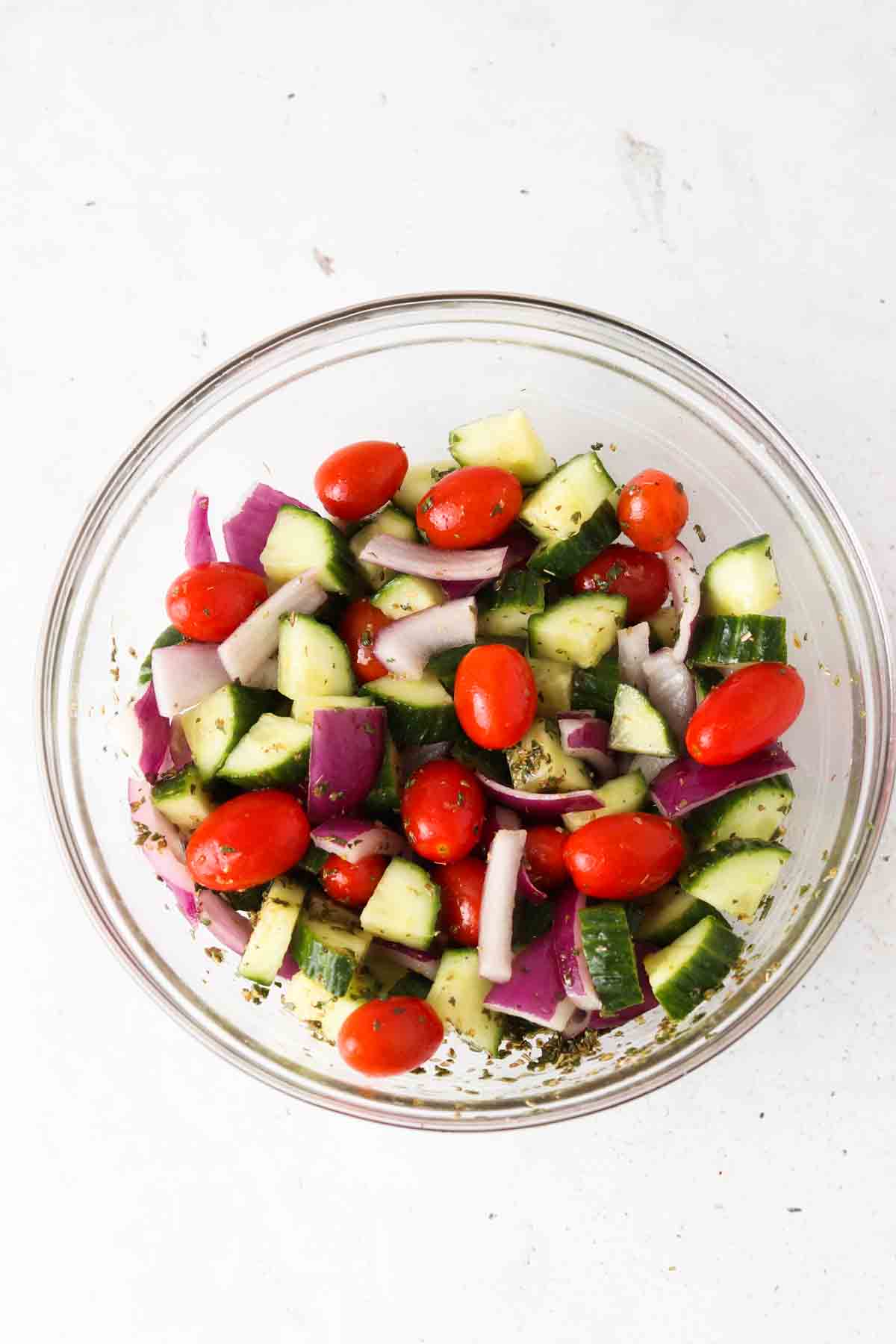 Greek salad ingredients in a bowl mixed together.