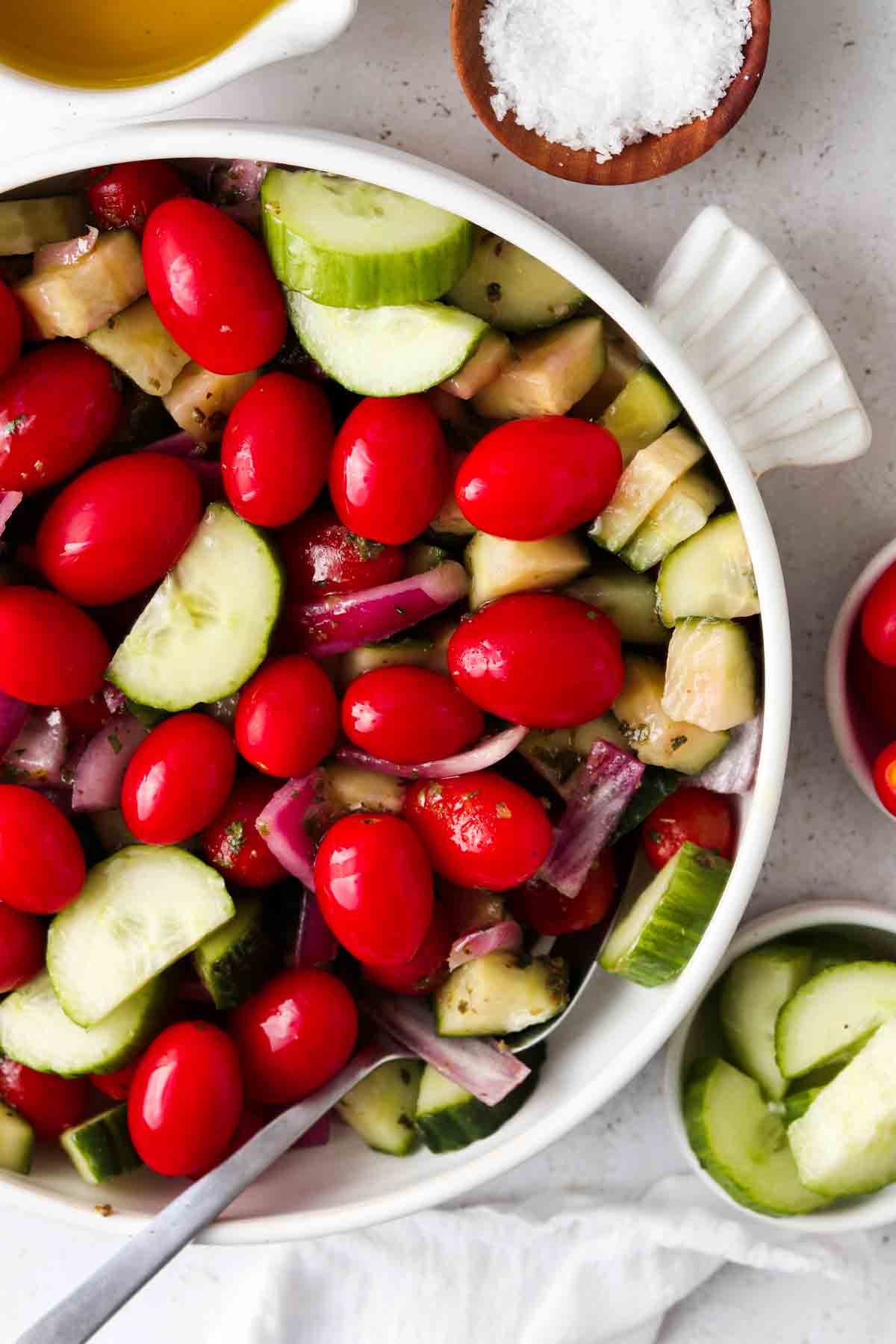 Whole30 greek salad in a white bowl with a spoon in it.