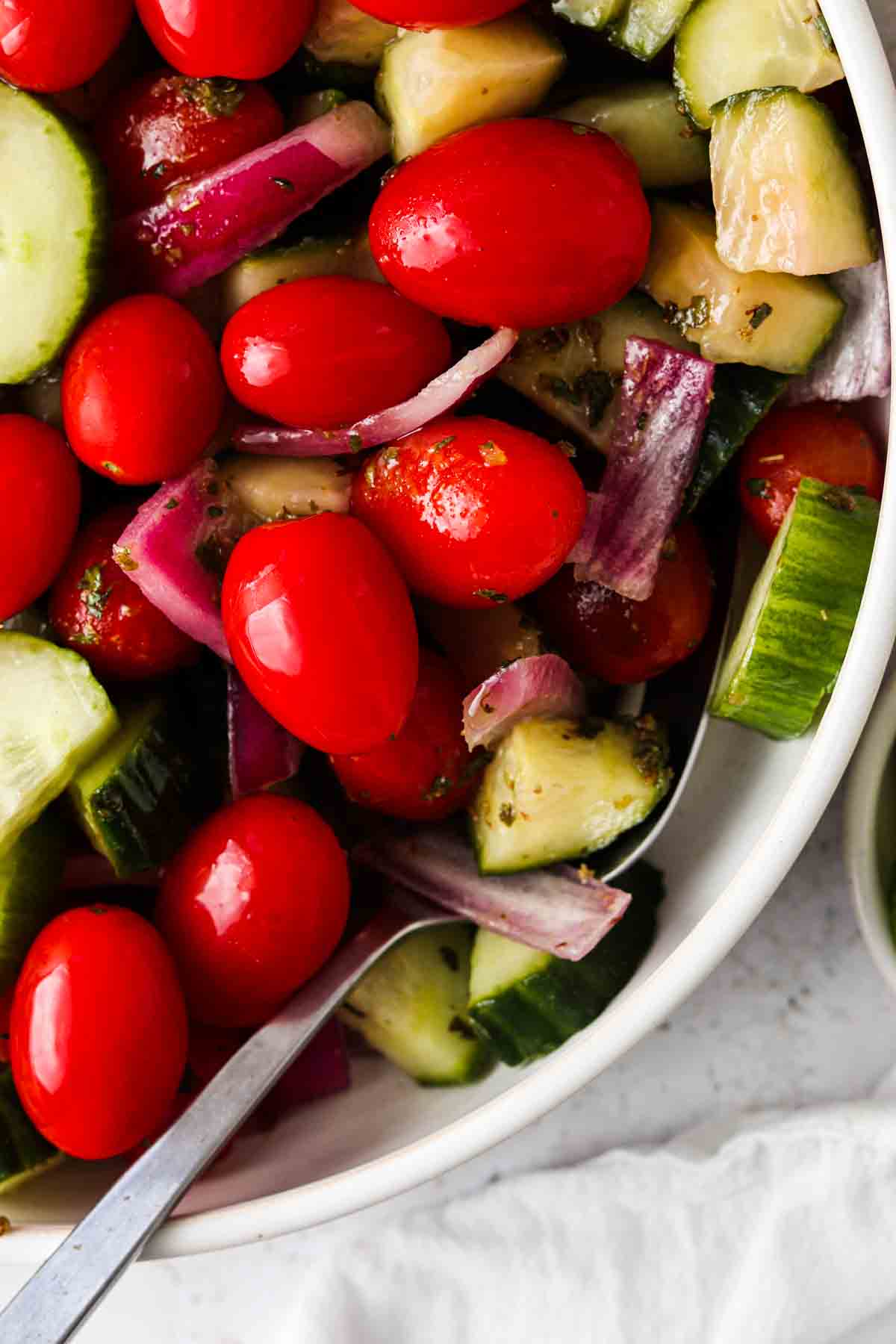 Greek salad in a white bowl with a spoon.