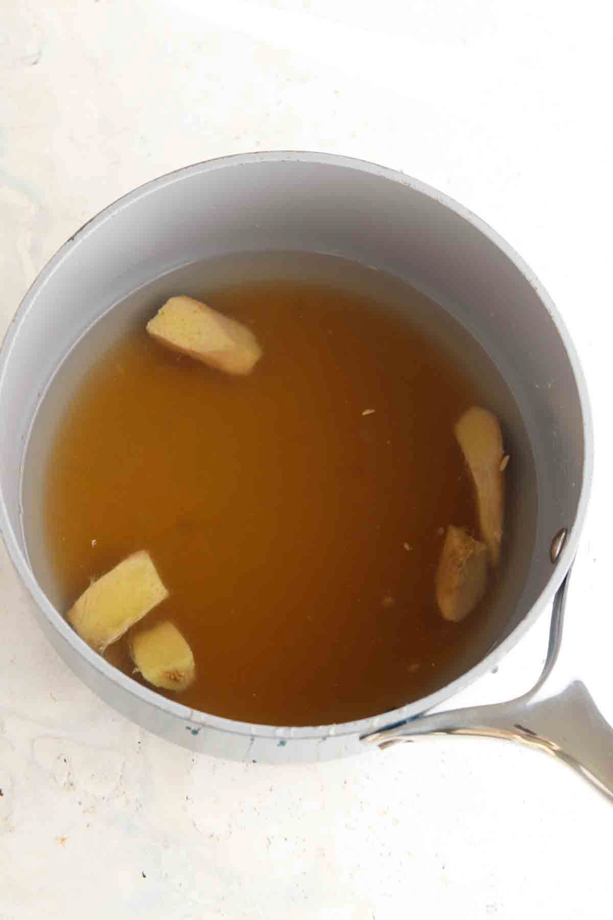Ginger, water, honey and lemon in a sauce-pot. 