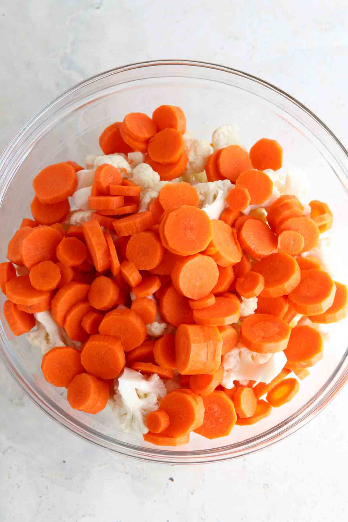 Coined carrots and cauliflower florets in a glass bowl.