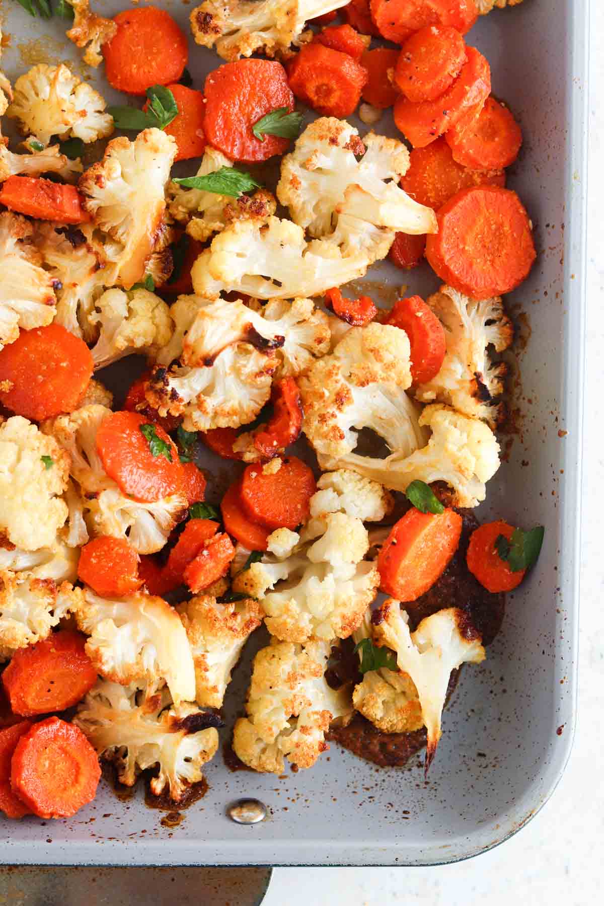 Roasted cauliflower and carrots on a sheet pan.