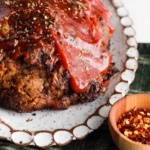 Meatloaf on a platter with ketchup glaze drizzled on top.