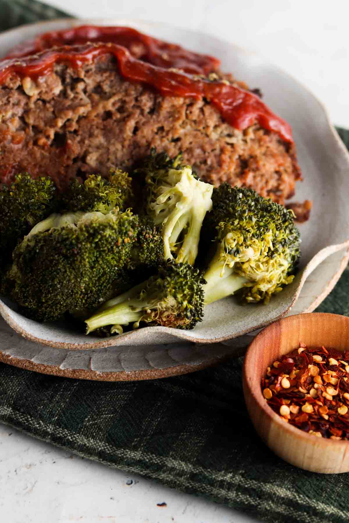 Gluten free meatloaf on a plate with a green napkin below it. 
