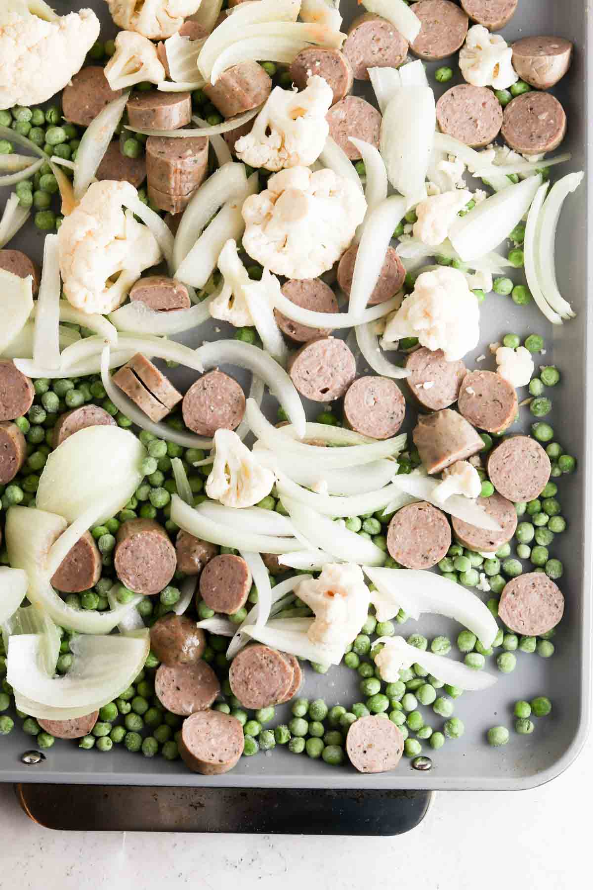 Onions, peas and chicken sausage on a sheet pan.