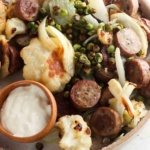 Chicken sausage and vegetables on a plate with dipping sauce.