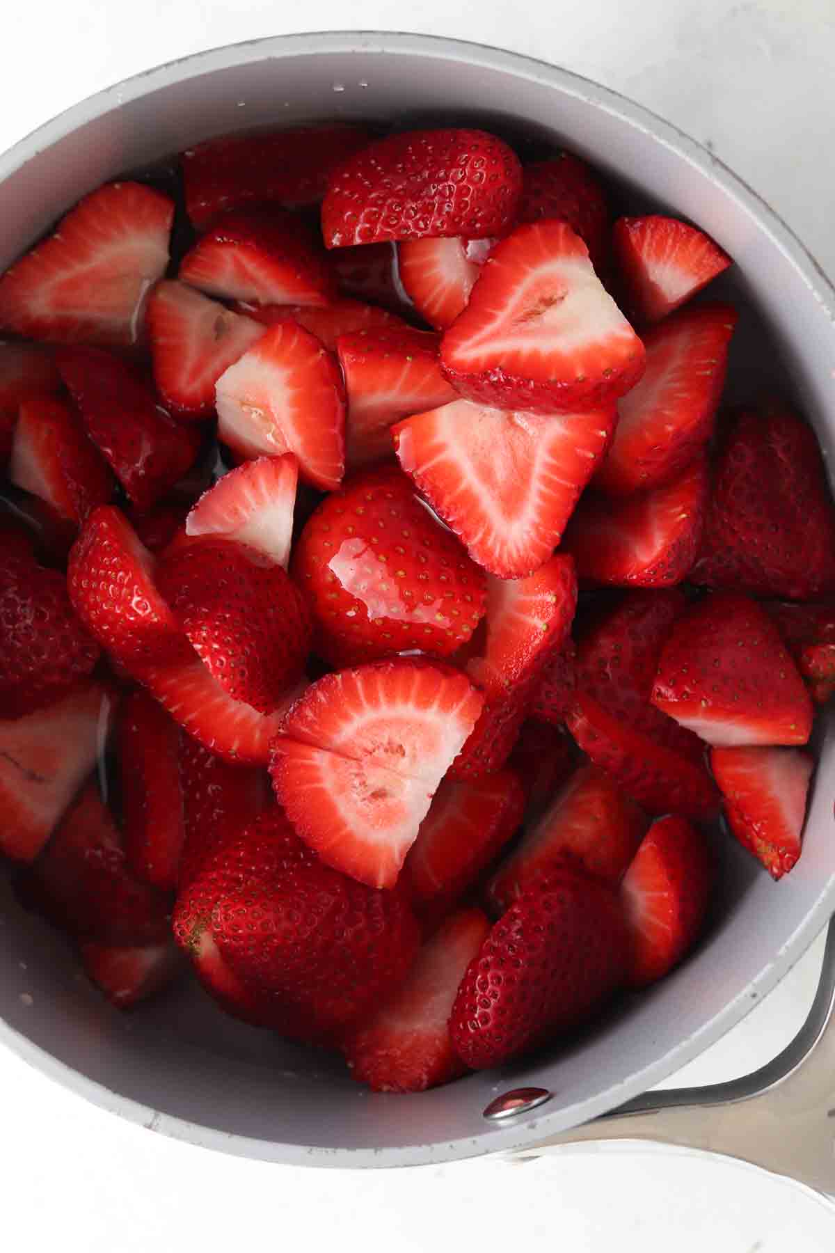 Strawberries, honey and water in a sauce pot.