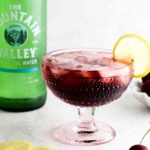 Cherry mocktail in a fun pink glass with a lime on top.