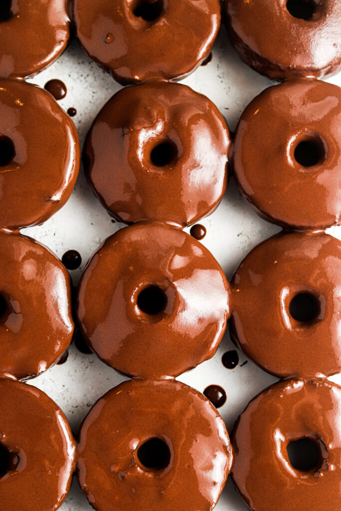 gluten free donuts lined up on the counter with chocolate frosting