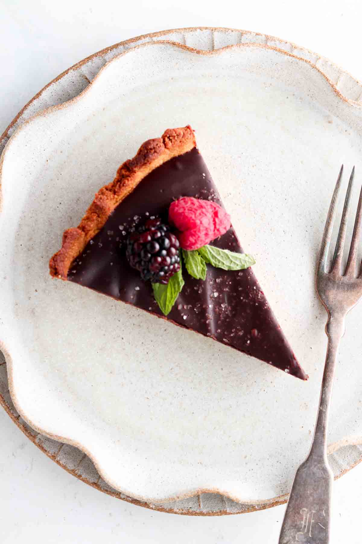 A slice of a chocolate tart on a grey plate.