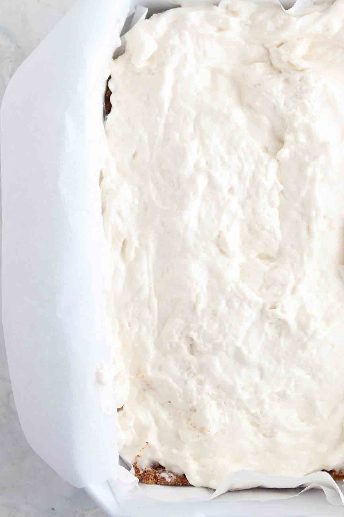 Marshmallow fluff spread out over a homemade cookie crust.