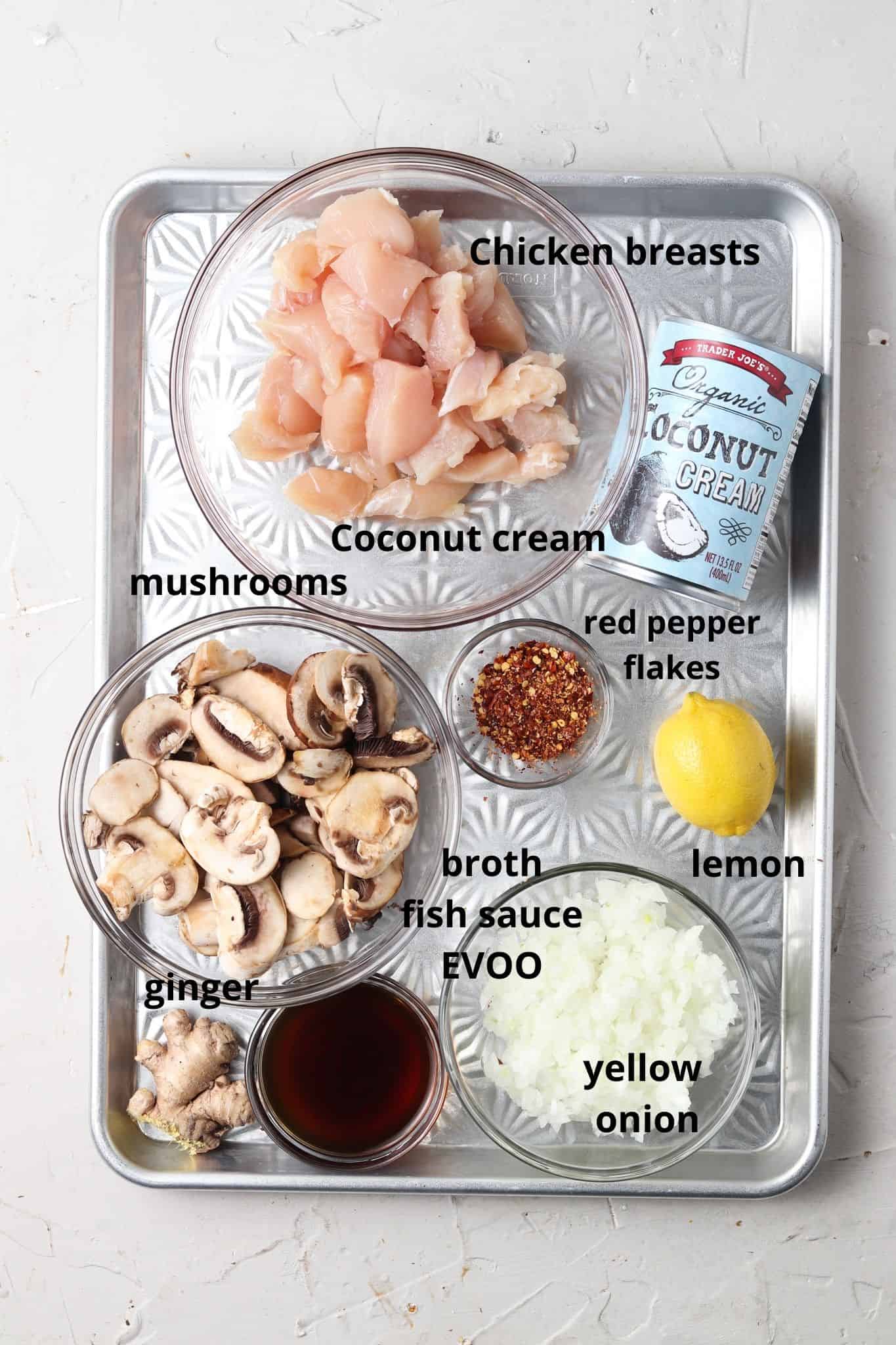 Thai creamy chicken soup ingredients in glass bowls on a silver tray. 