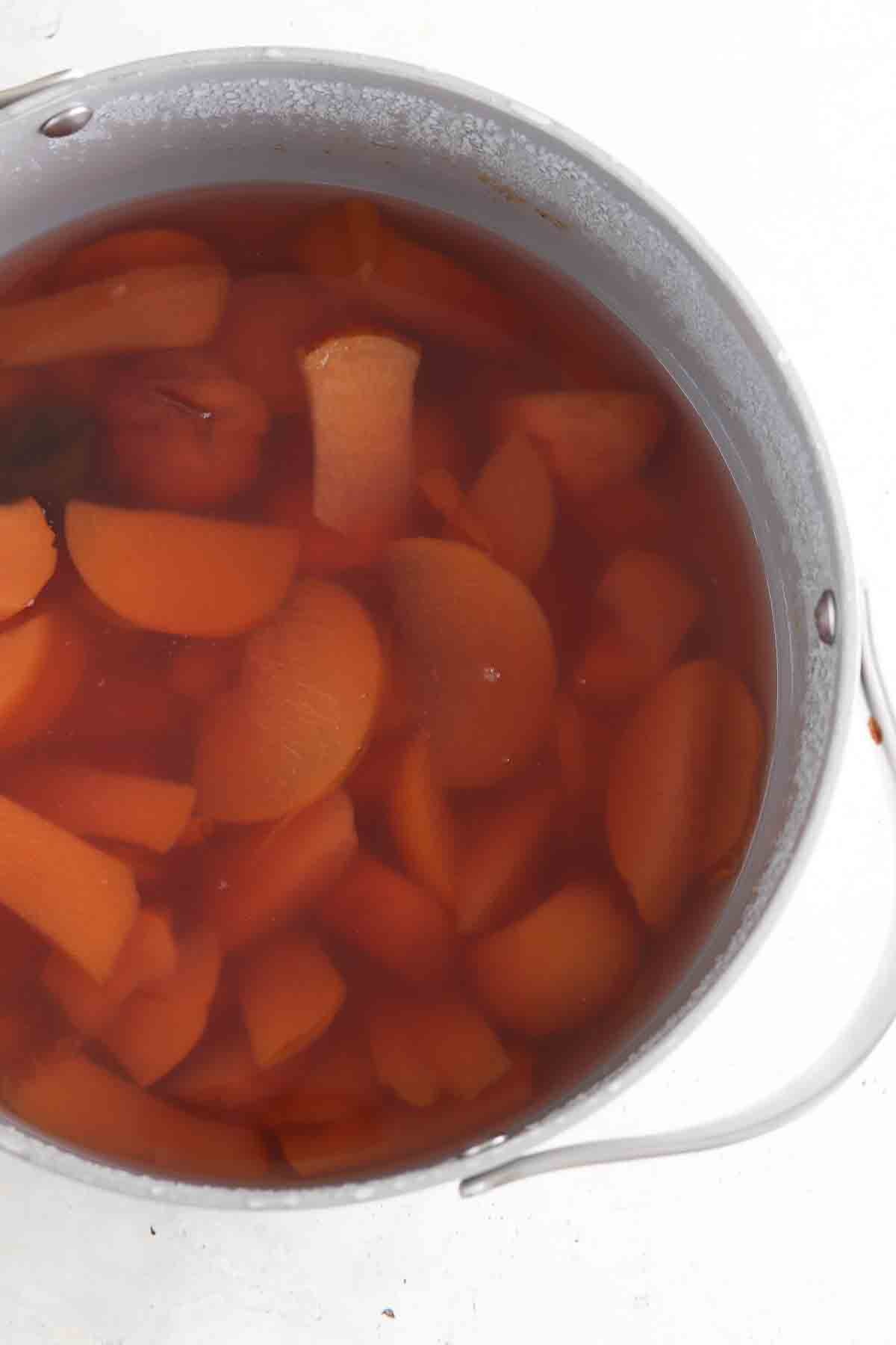 Peach simple syrup in boiled in a large bowl.