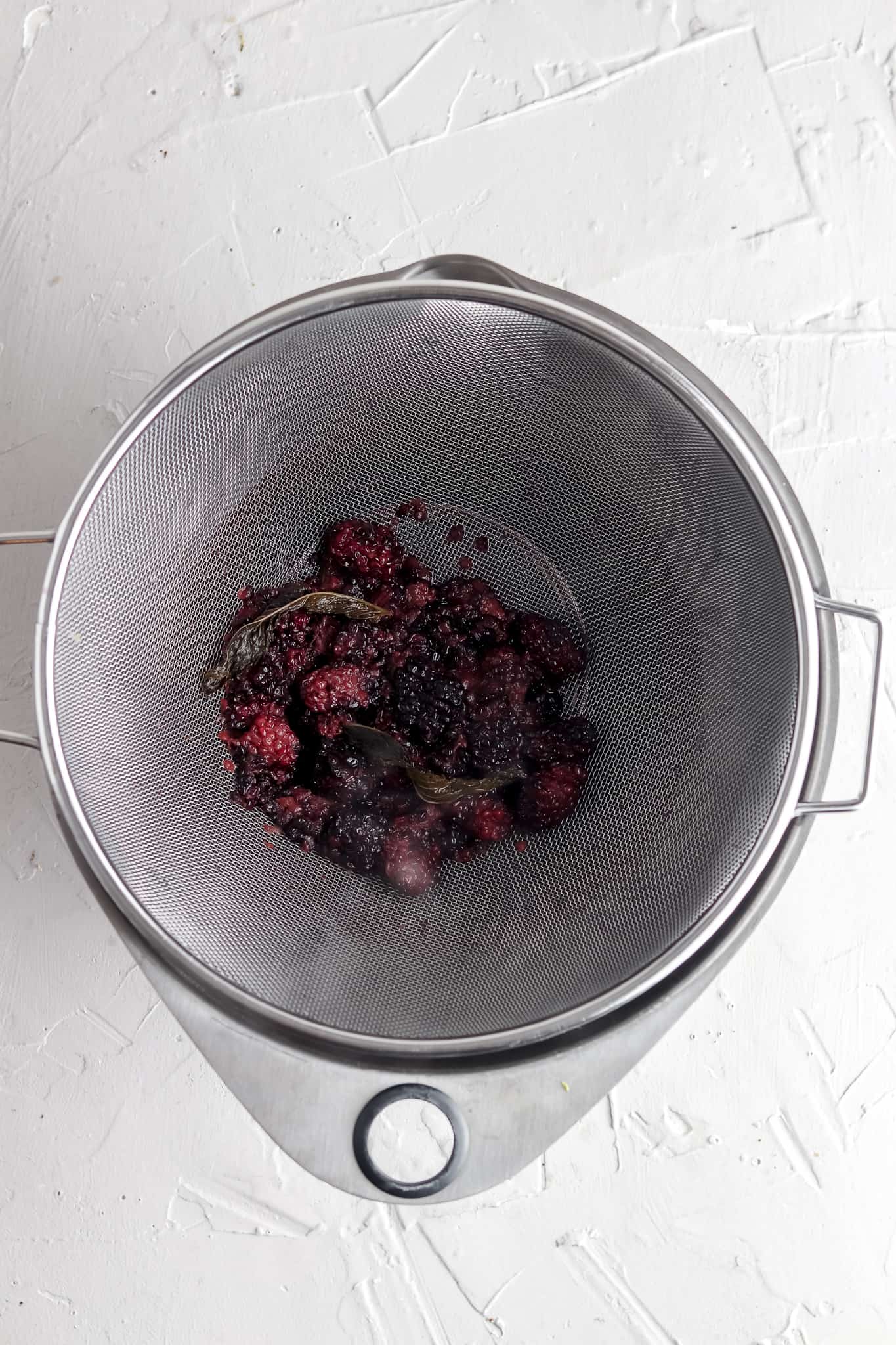 Simple syrup being strained over a metal strainer. 