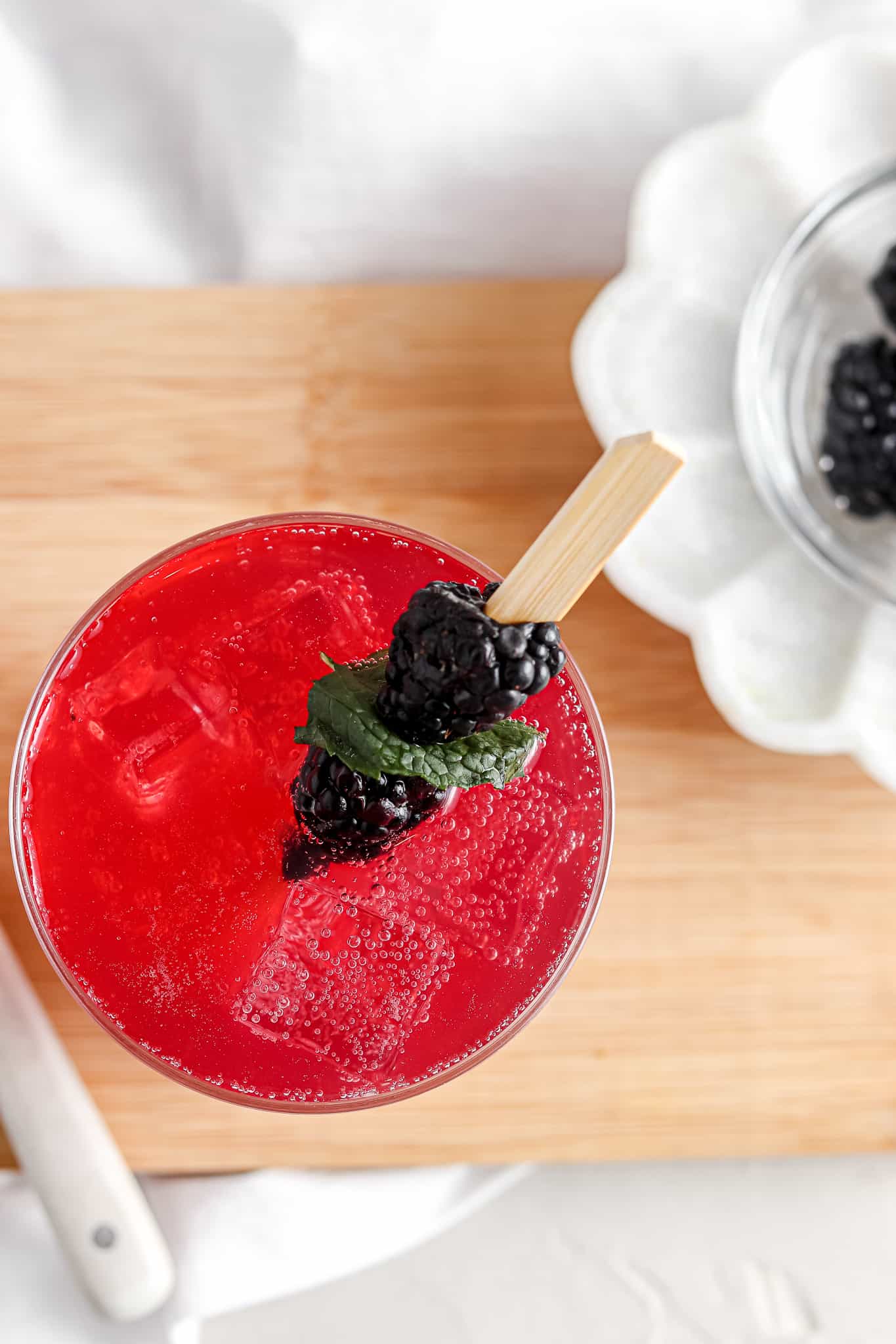 Overhead shot of a blackberry mojito in a glass with blackberries on top.