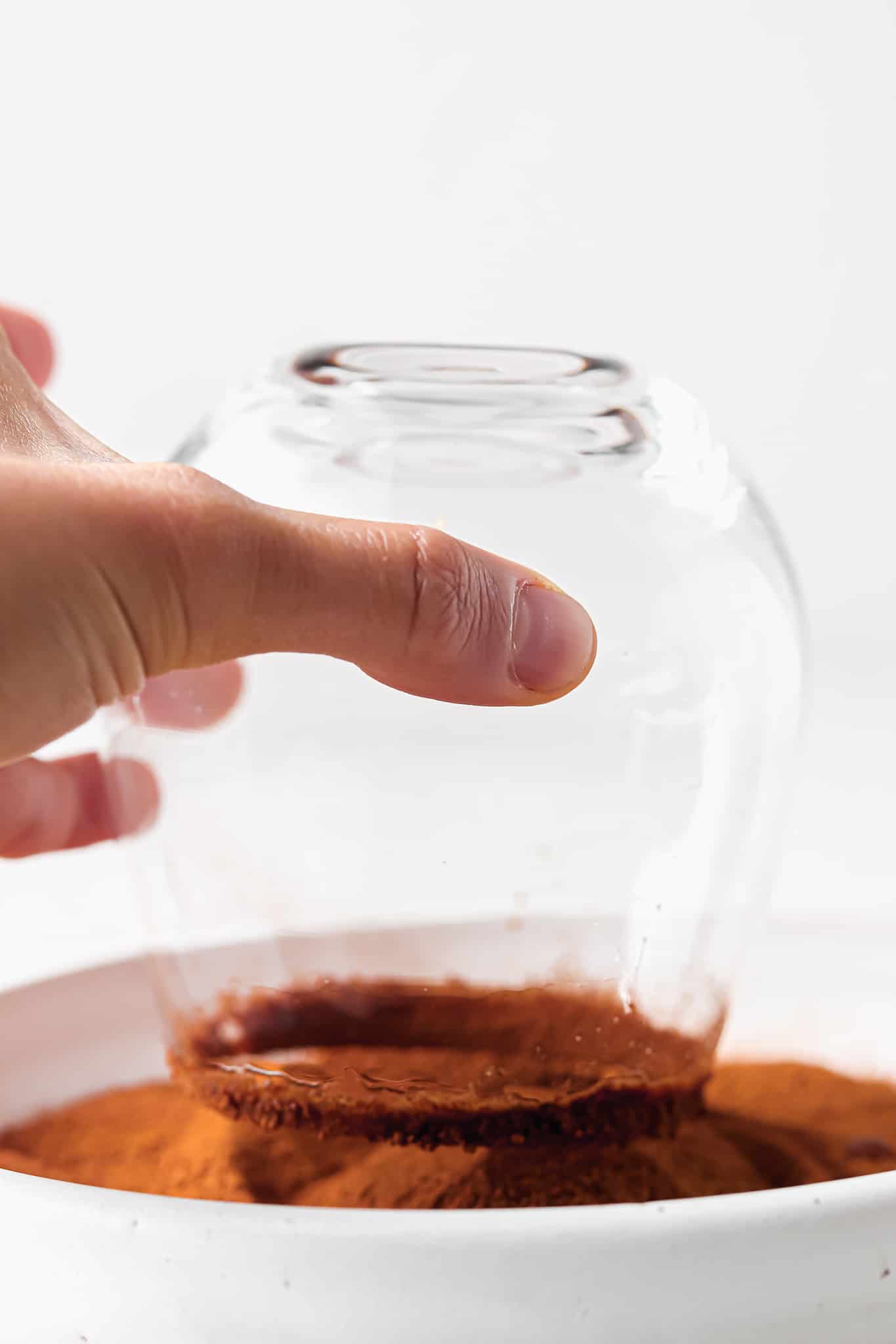 Coconut sugar and cinnamon mixed in a bowl  on a plate with a glass dipped in it. 