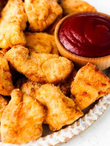 chicken nuggets on a plate with ketchup