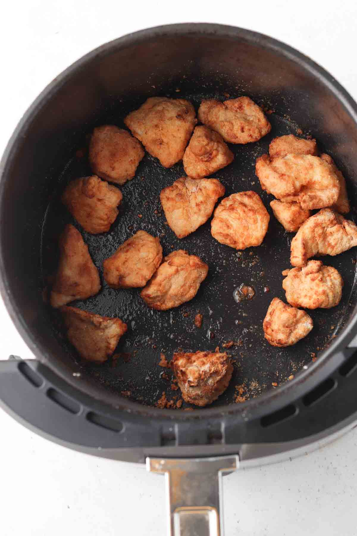 Crispy chicken nuggets in an air fryer basket.