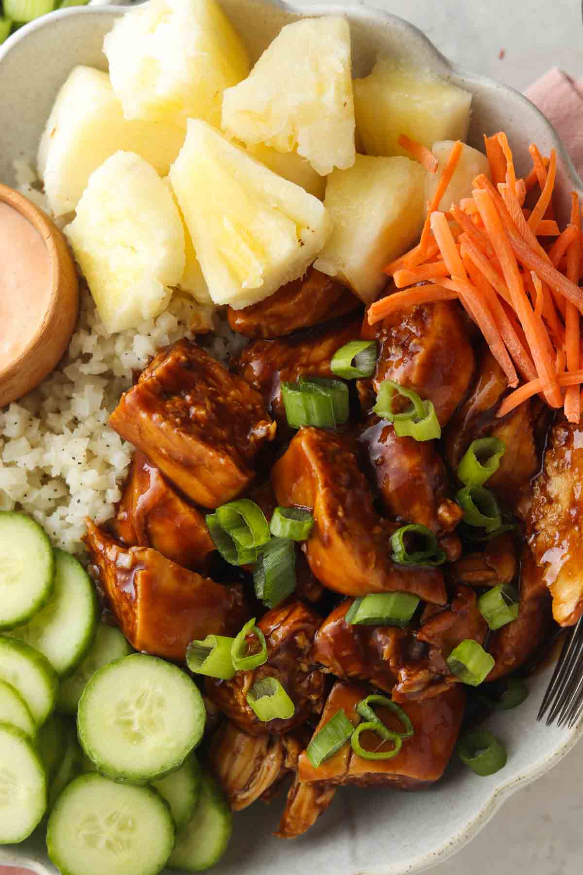 Marinated chicken bowls with cauliflower rice, green onions, carrots, pineapple and cucumbers.