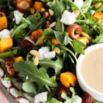 Arugula salad with squash, feta sheet, pine nuts and dates on a plate.