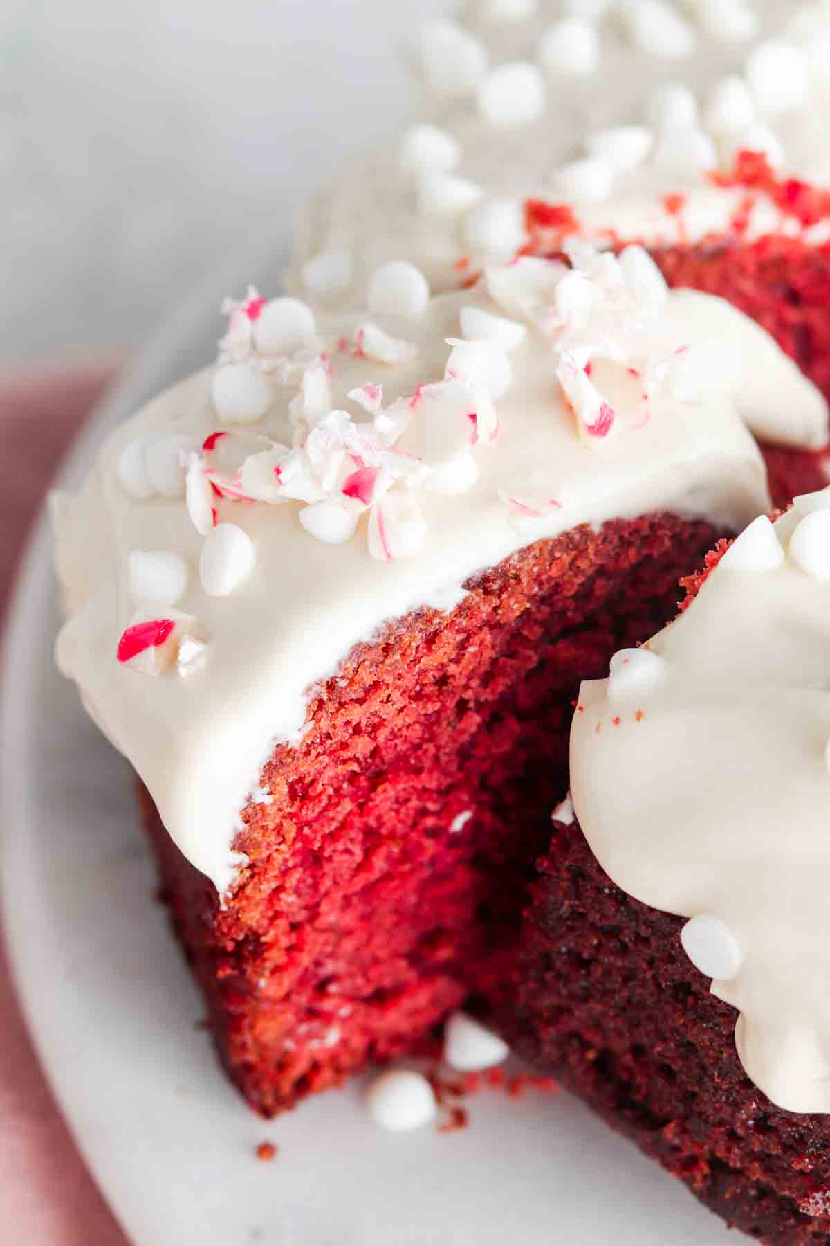 Slice of red velvet cake on a platter with candy canes on top.
