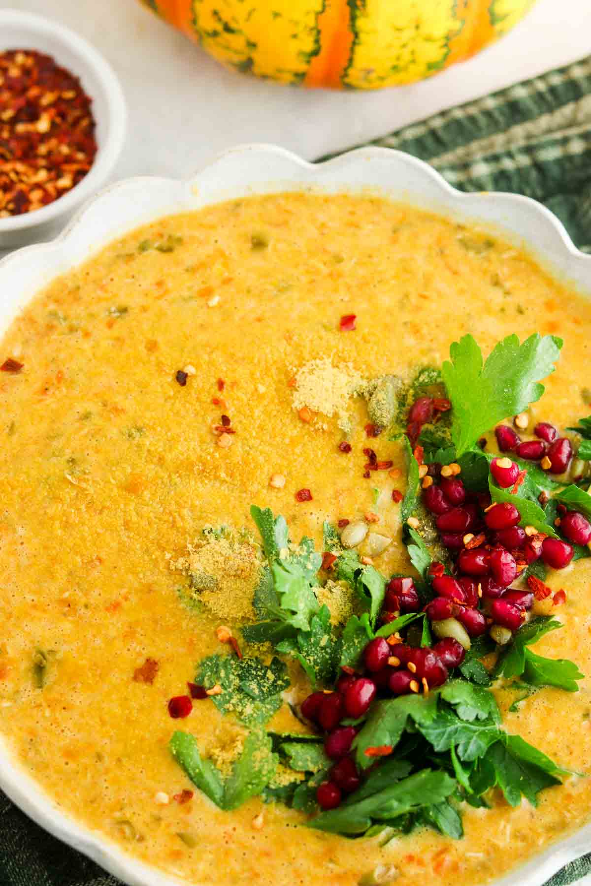 Carrot pumpkin soup in a bowl with fresh herbs on top.