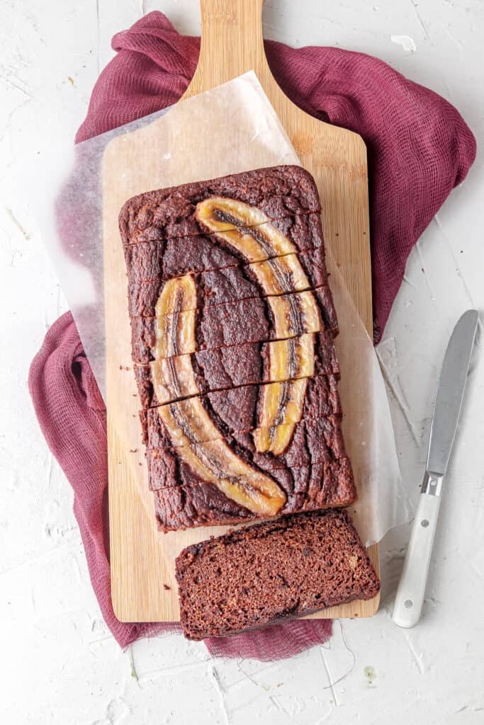 whole chocolate banana bread cut up on a wooden board