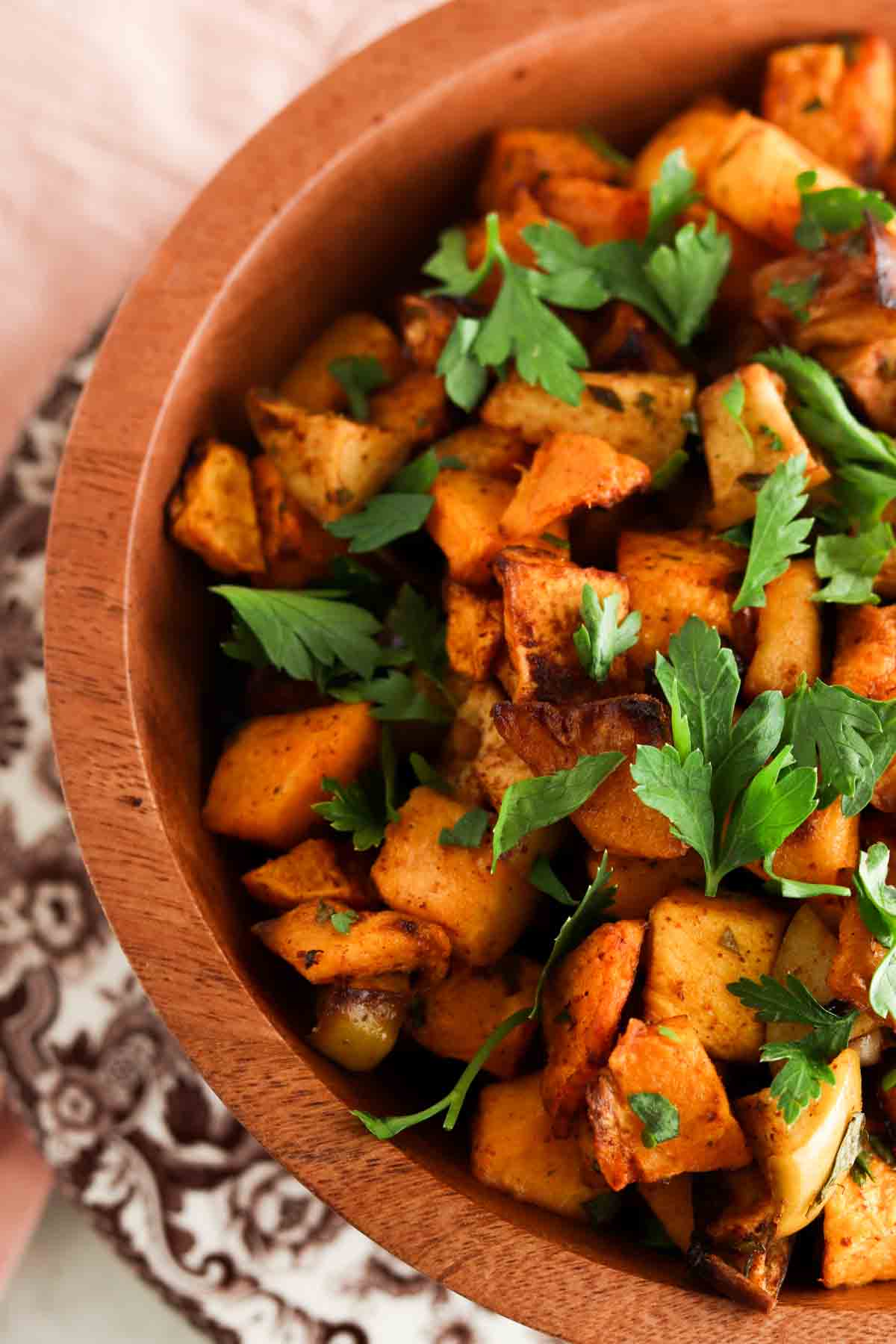 Butternut squash in a large brown bowl with parsley on top.