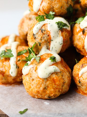buffalo chicken meatballs stacked on top of each other with whole30 ranch and parsley