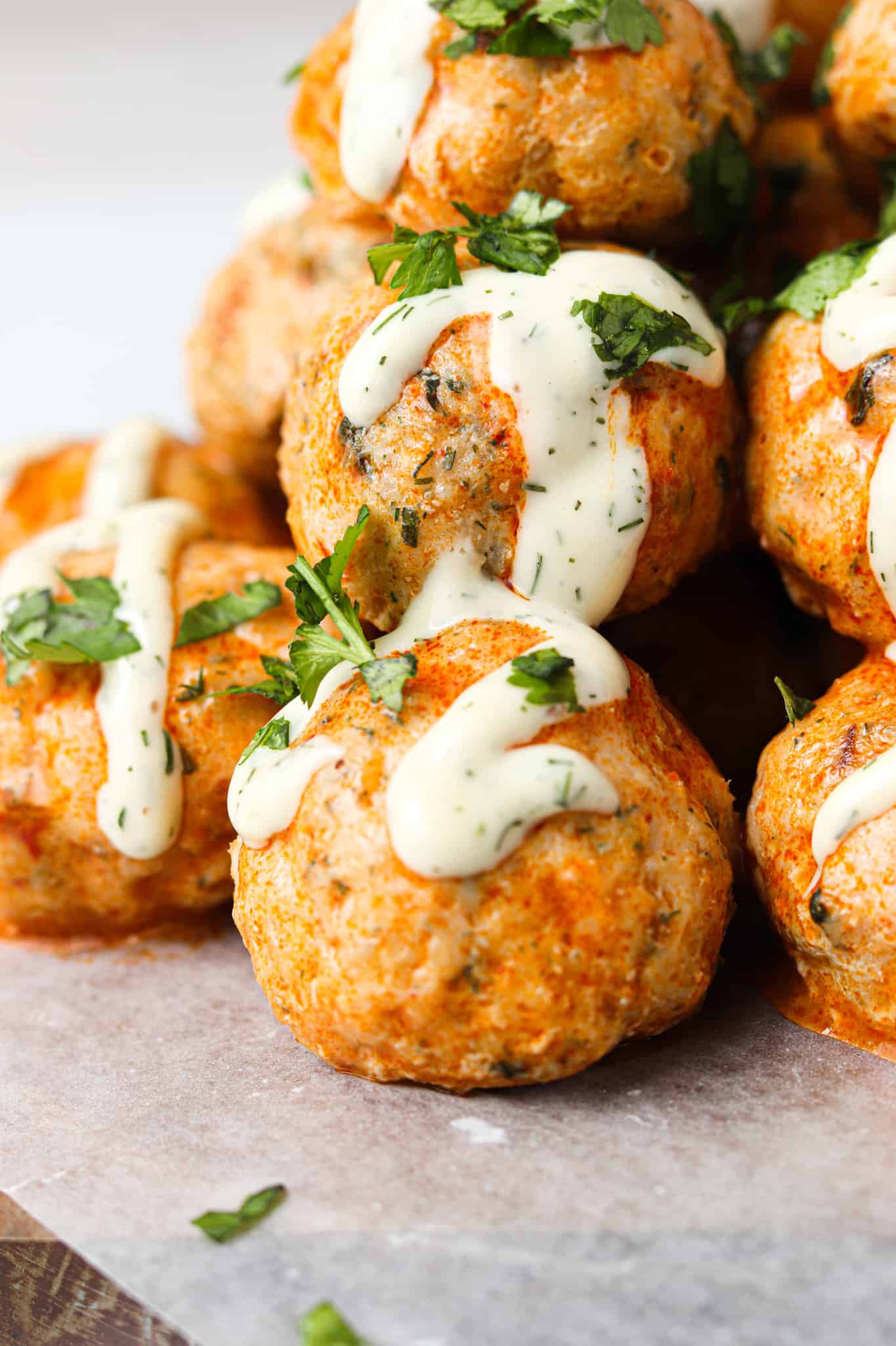 Buffalo chicken meatballs stacked on top of each other with whole30 ranch and parsley.