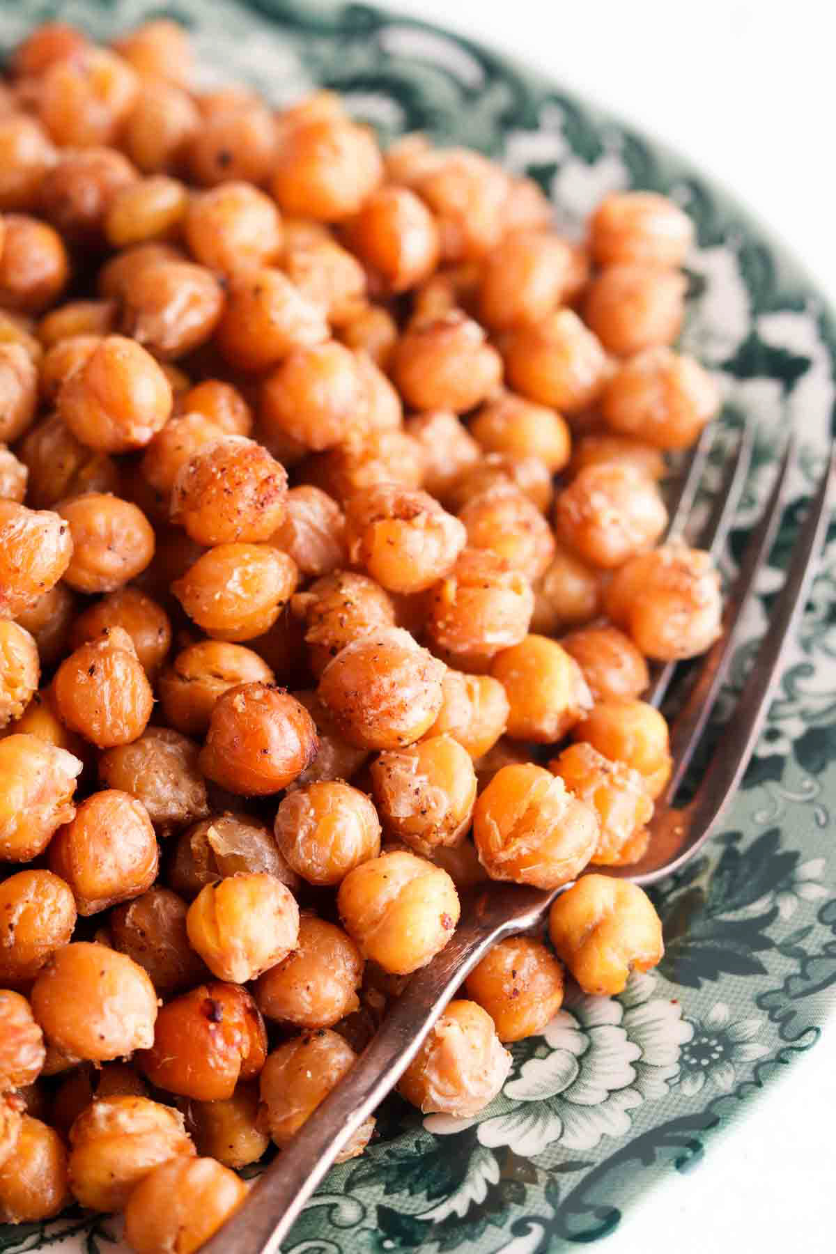 Crispy chickpeas on a green and white plate with a fork on the right side.
